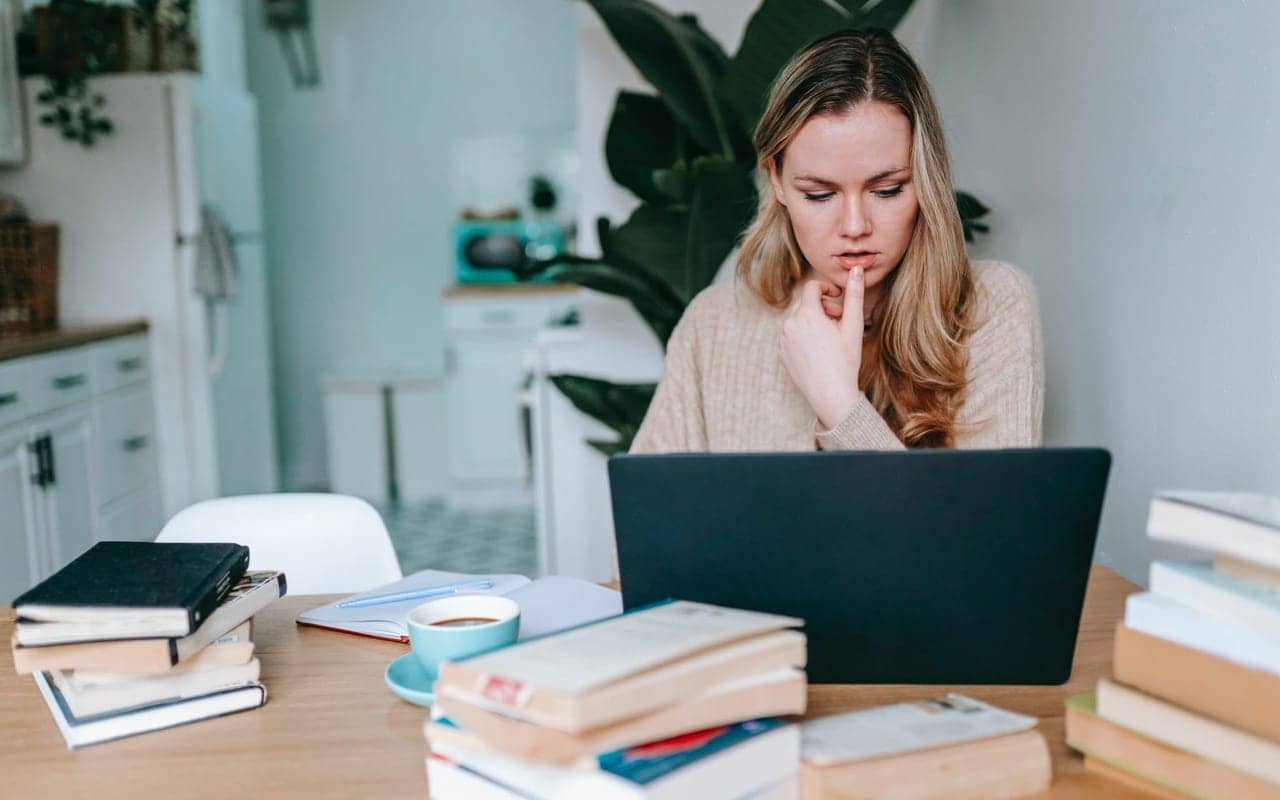 a woman is learning with a laptop and books