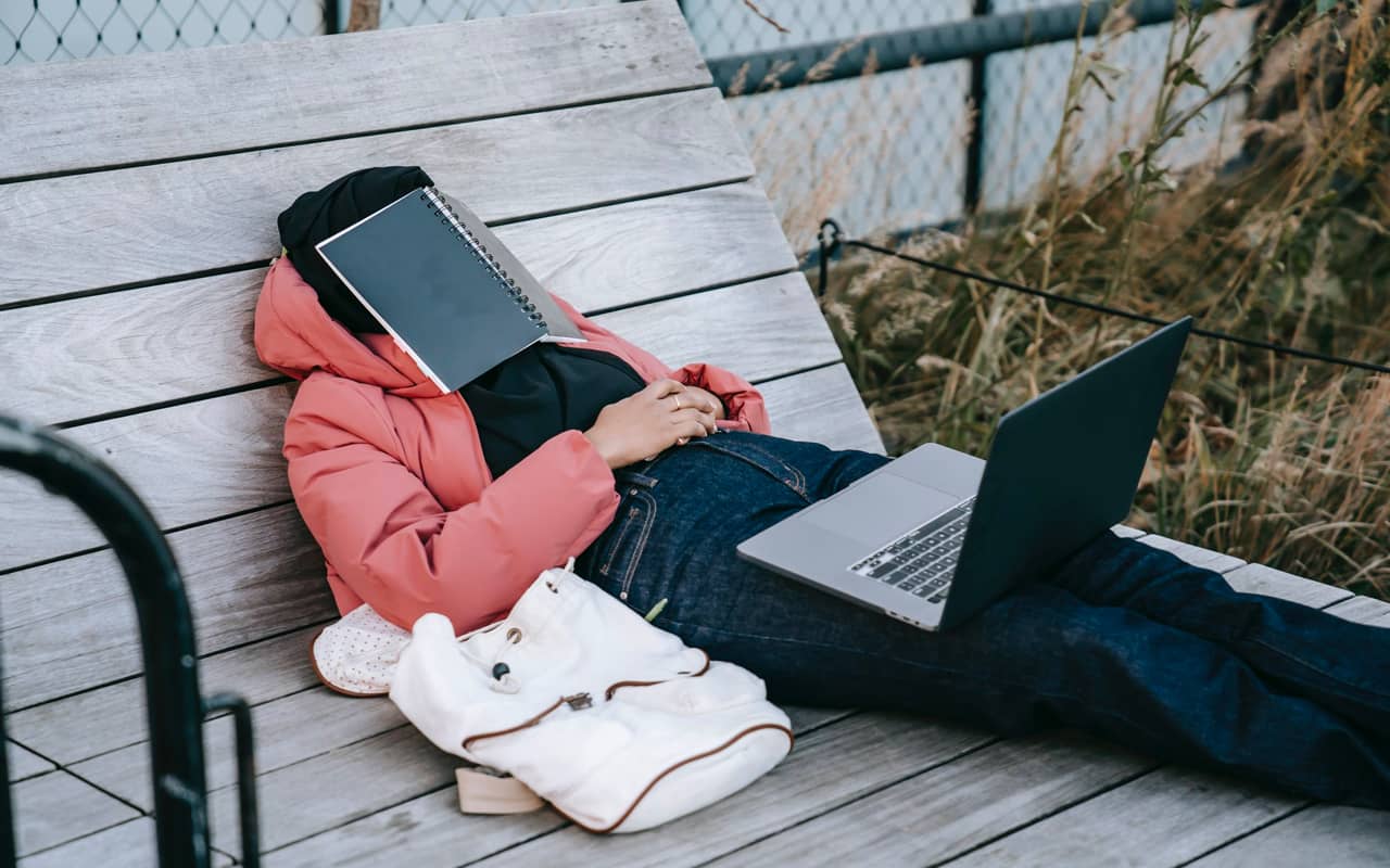a woman is resting with a book on her face