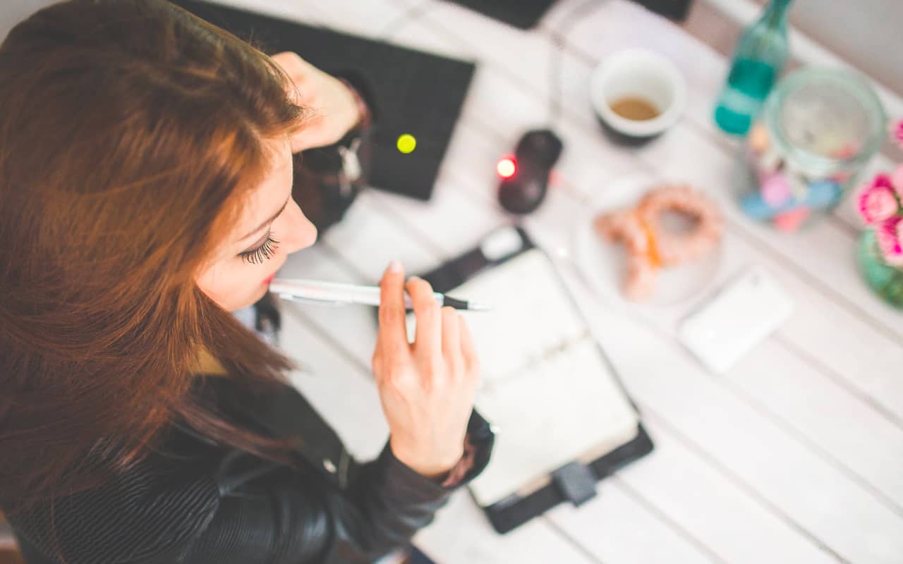a woman is thinking with a pen in her hand