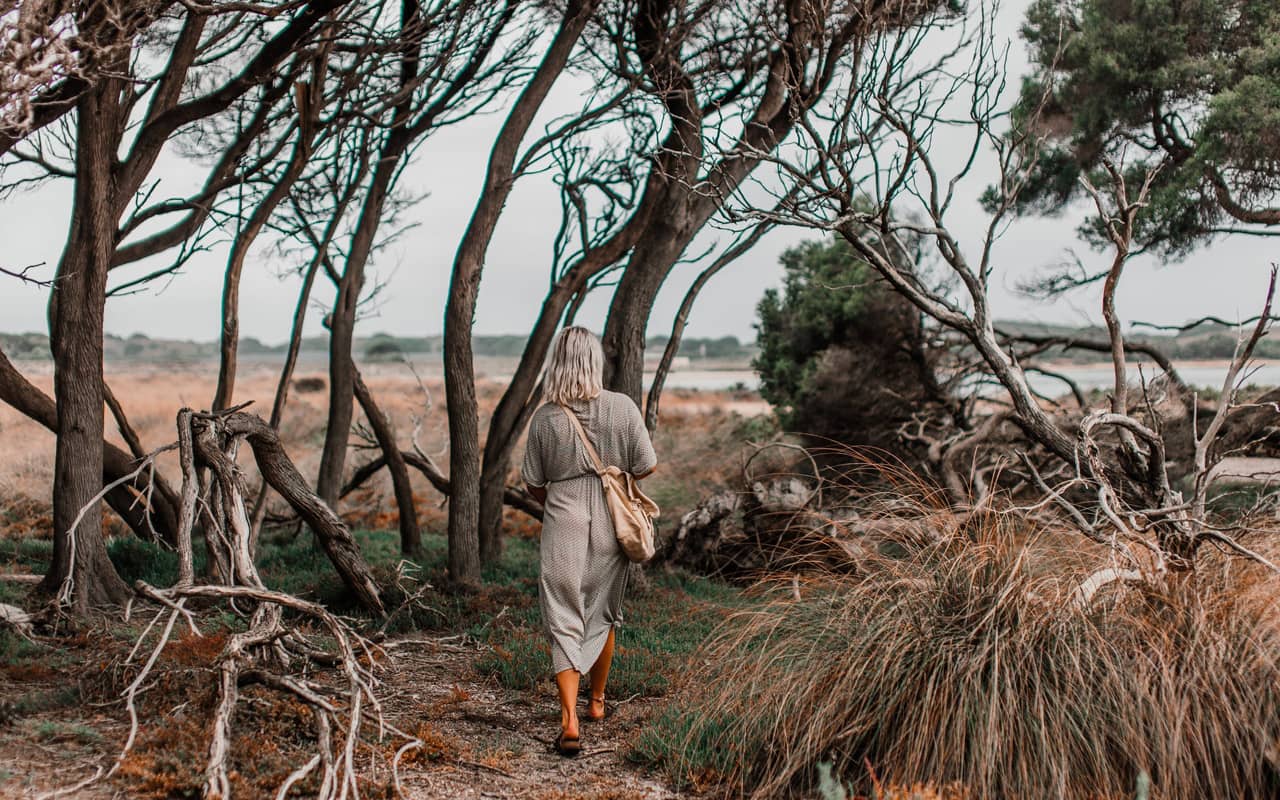 a woman is walking between tree roots