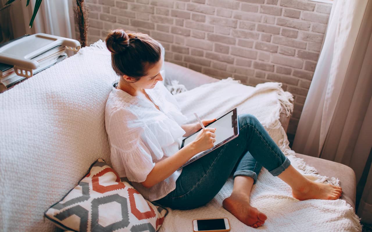 a woman is sitting on a sofa and drawing