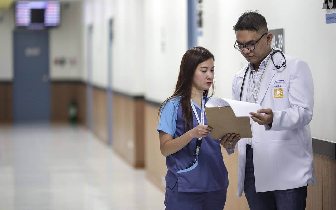 A doctor and their assistant check a patient's chart.