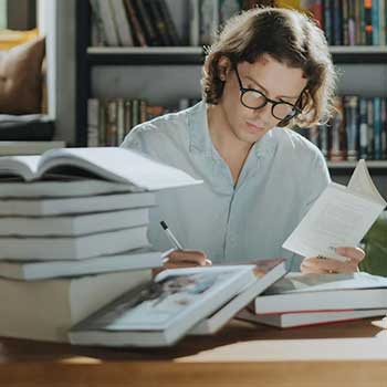 holistic learning feature image of a man taking notes with a pile of books