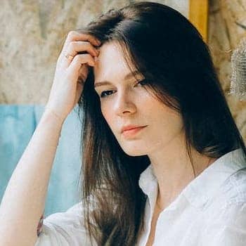 how to improve critical thinking feature image of a woman with a hand raised to her forehead looking thoughtful