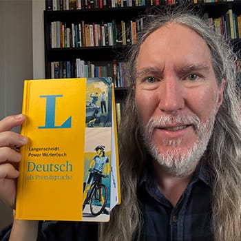 Anthony Metivier holding a German dictionary for the language learning hacks feature image