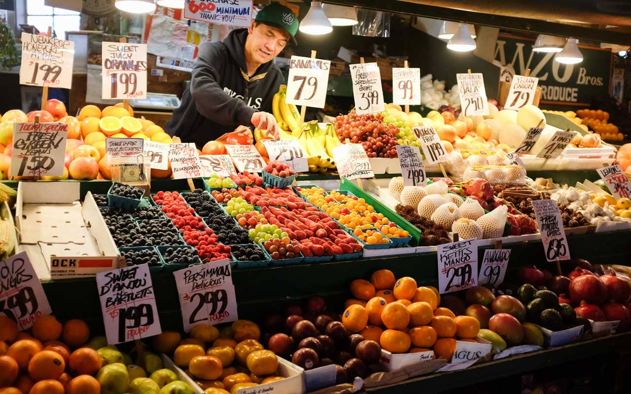 A man restocks produce at a market.
