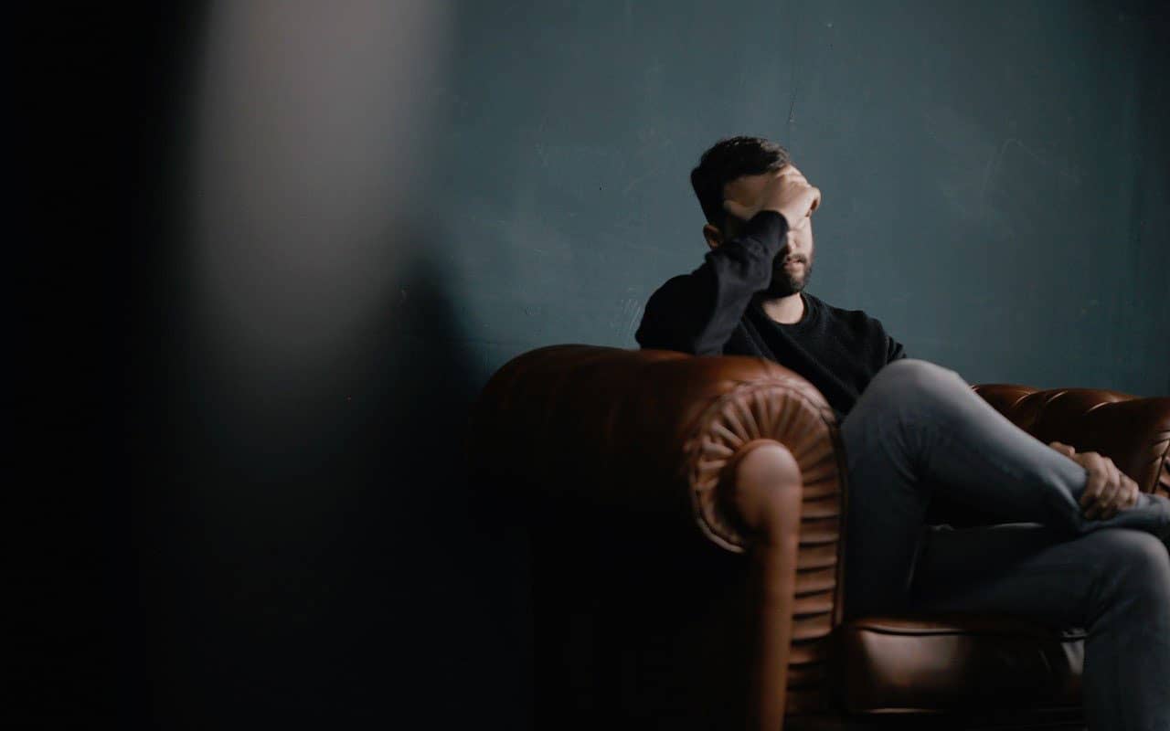 A young man sits with a hand on his forehead. Frustration with symptoms can come along with a memory disorder diagnosis.