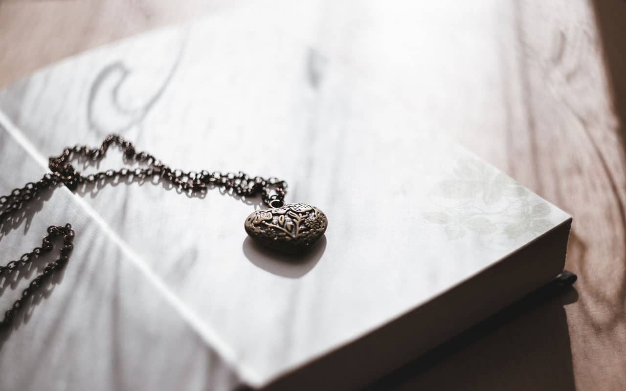 A chain lays on top of an open book. The linking method is much like the links in a necklace.