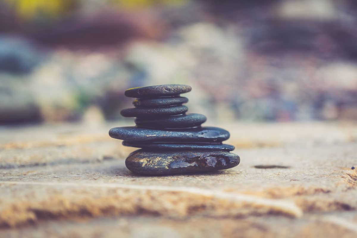 A stack (or cairn) of smooth river rocks sits on a flat sandy surface.