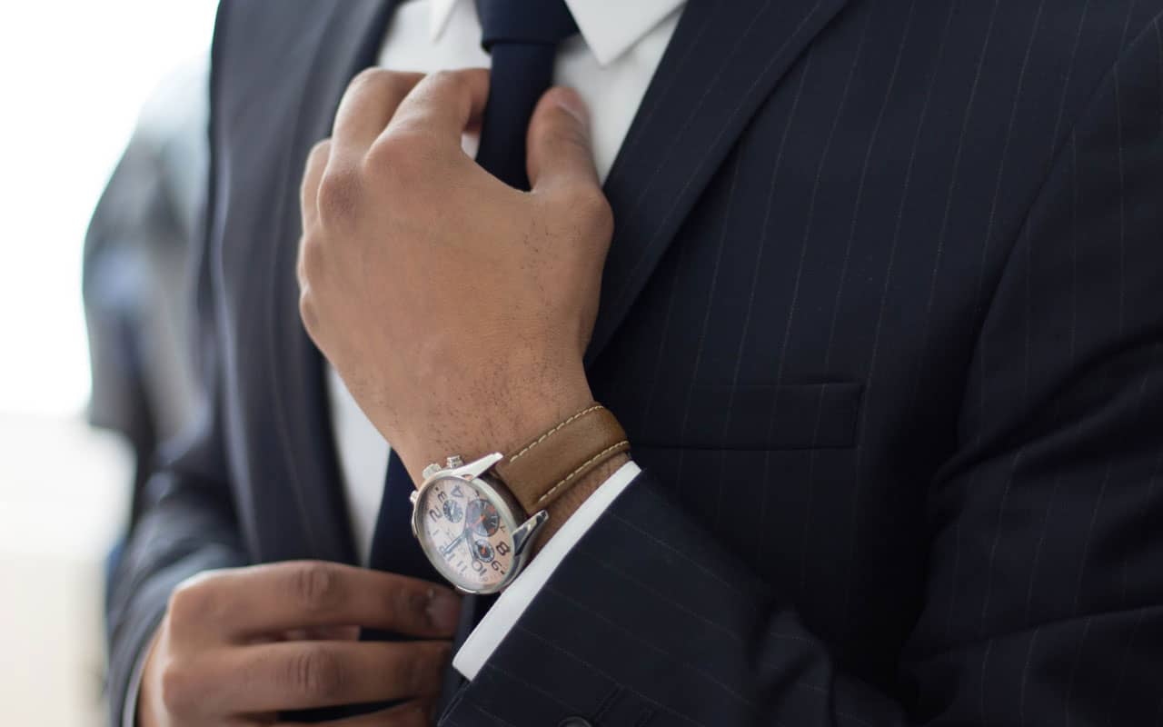 A man adjusts the tie of his suit.