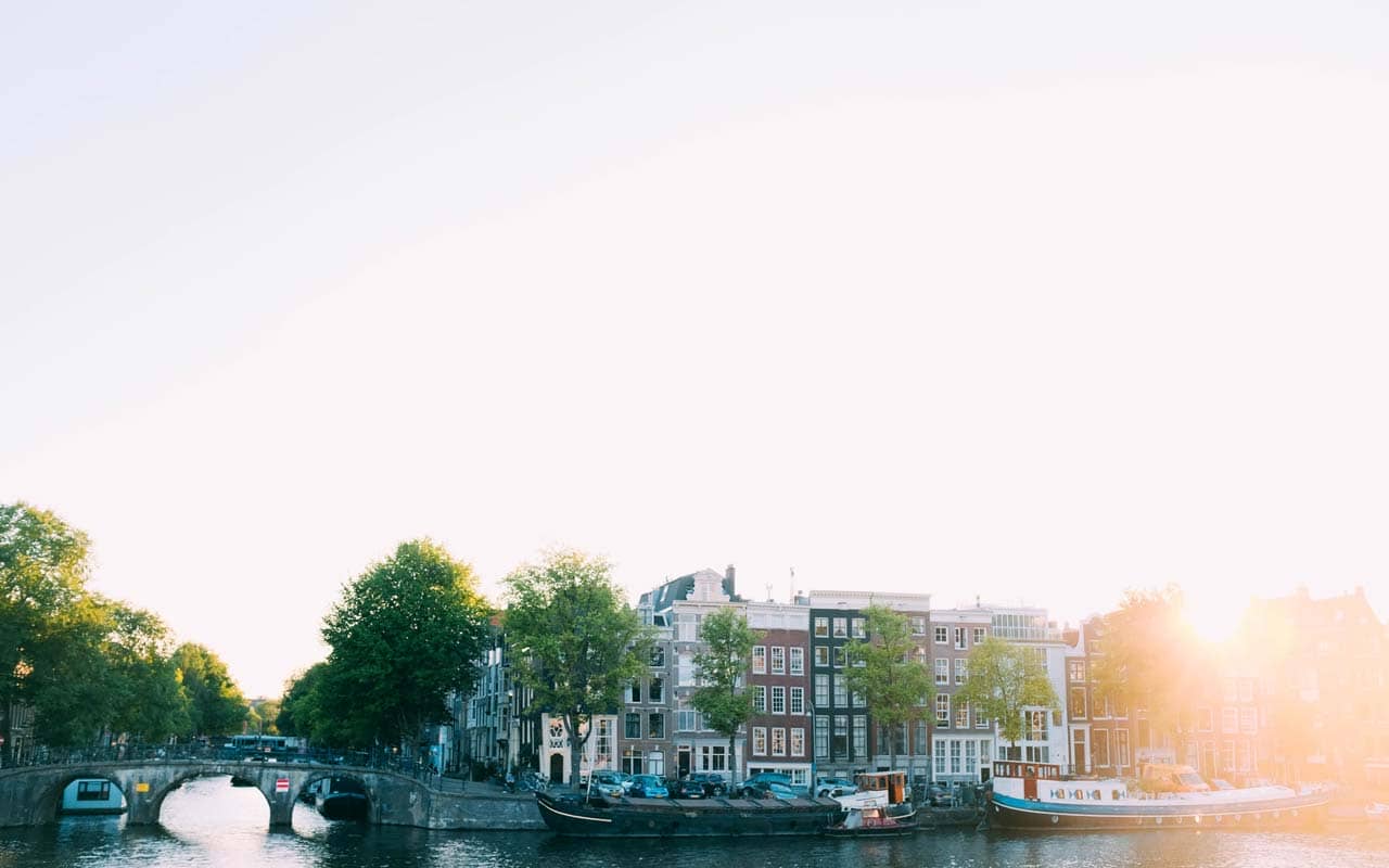 The sun rises over a neighborhood along a canal. The weather is an easy place to start learning Spanish vocabulary.