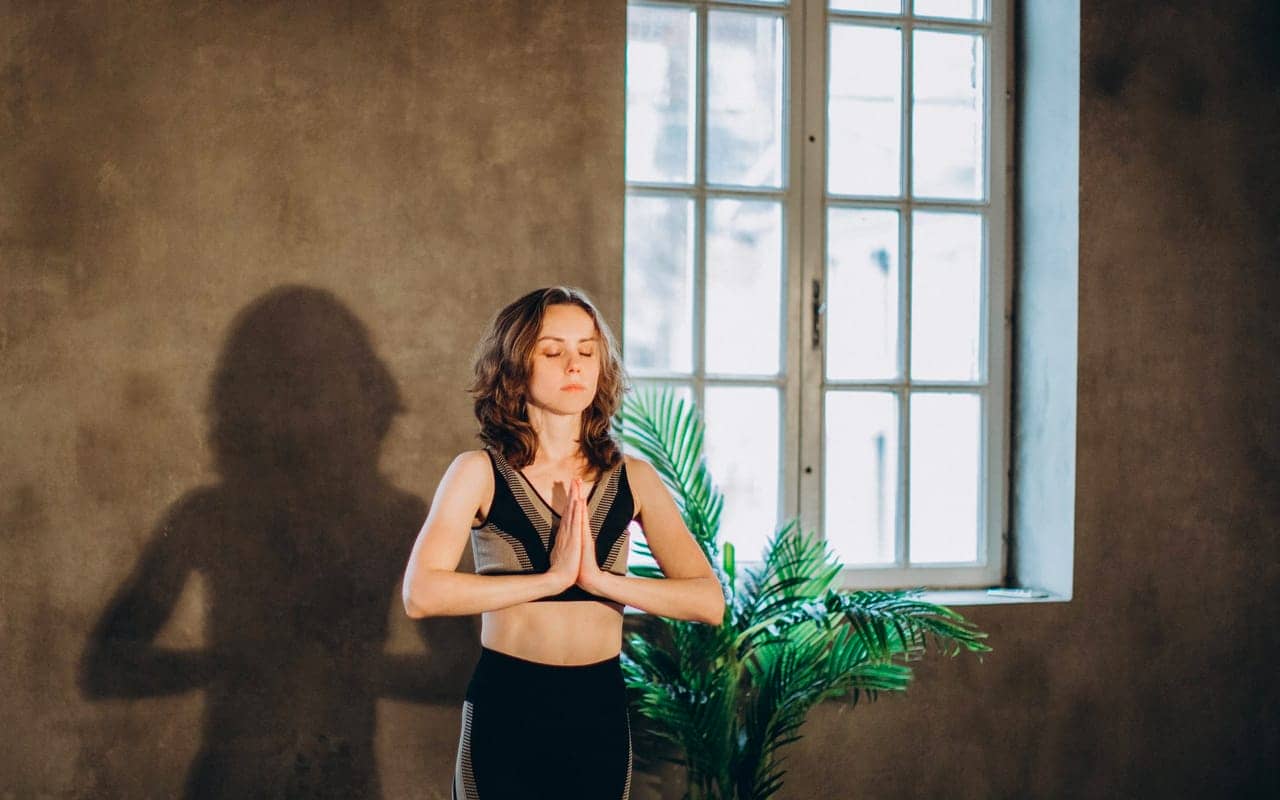 woman is meditating in front of a brown wall